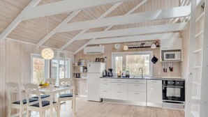 Een moderne keuken met witte kastjes, een eethoek met tafel en stoelen, en een groot raam voor natuurlijk licht.