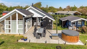 Een moderne woning met een terras, buitenmeubels en een jacuzzi.
