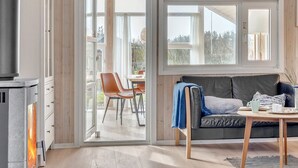 Een moderne woonkamer met een open haard, een bank, een eettafel en een groot raam.