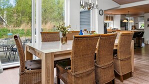 A dining area with wicker chairs, a glass-top table, and a chandelier. - "Sigfred" - 1.5km from the sea by Interhome (Hals)