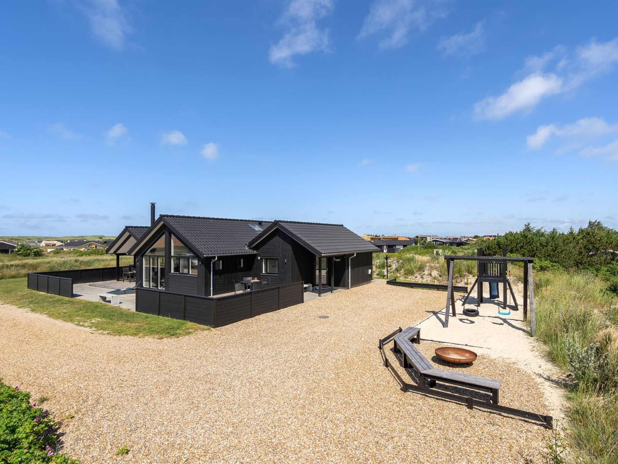 A modern two-story house with a covered patio and a play area.