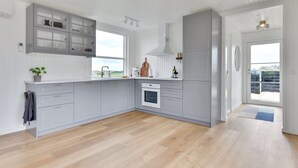 Une cuisine moderne avec des meubles gris, une grande fenêtre et une vue sur l’extérieur.