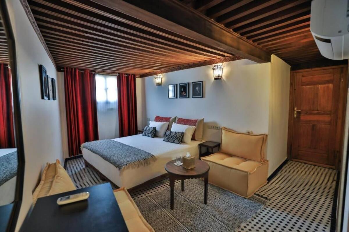 A hotel room with a bed, sofa, and a small table.