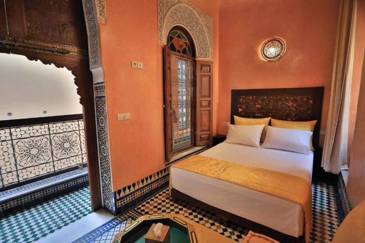 A room with a bed, a decorative door, and a patterned floor.