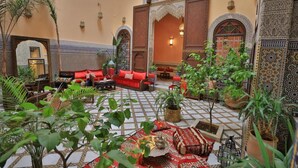 A traditional Moroccan interior with a tiled floor, red sofas, and ornate wall decorations. - Riad Moulay Driss et GiacomoOpens  (Fes)