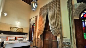 A traditional room with a bed, patterned walls, and a large wooden door. - Riad Moulay Driss et GiacomoOpens  (Fes)
