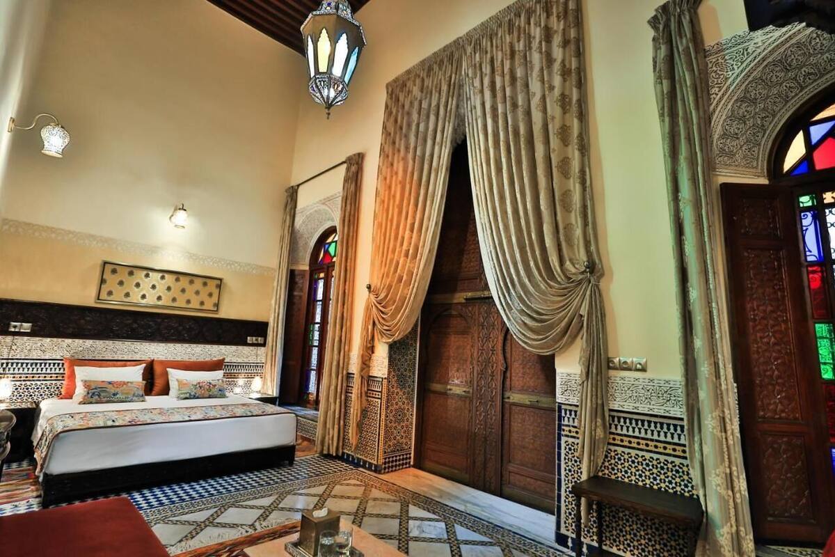 A traditional room with a bed, patterned walls, and a large wooden door.