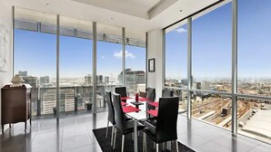 A modern dining area with a panoramic city view, large windows, and a minimalist design. - Perfect 4-bed Penthouse w/ Parking, Pool and Gym (Melbourne)