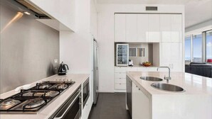 A modern kitchen with white cabinetry, a gas stove, a refrigerator, and a sink. - Perfect 4-bed Penthouse w/ Parking, Pool and Gym (Melbourne)
