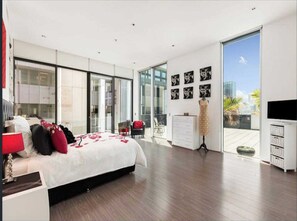 Relax in a spacious room with a large bed, flat-screen TV, and sliding glass door to a balcony.