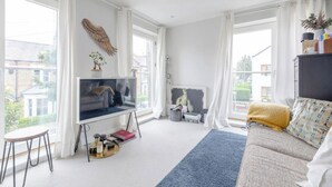 Een moderne woonkamer met een grote televisie, een bank en een raam met gordijnen.