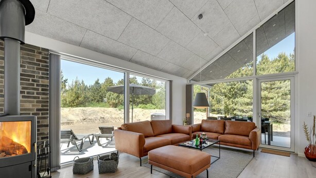 Una sala moderna con chimenea, sofá de cuero y ventanas amplias que ofrecen vistas al exterior.