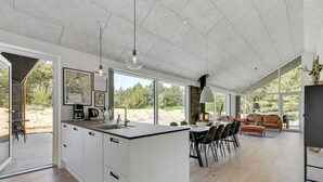 Una cocina amplia con una isla grande, comedor con sillas y sala de estar con sofá y mesa de centro.