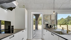 Una cocina moderna con armarios blancos, encimera negra y vistas al exterior.