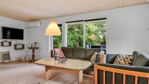 Un salon moderne avec un plafond en bois, une grande fenêtre, un canapé, une table basse et un téléviseur.