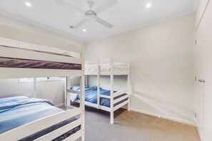 A bedroom with bunk beds, a ceiling fan, and a window.