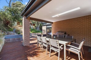 An outdoor patio with a brick wall, a glass door leading to a pool, and a barbecue grill.