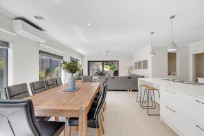 A modern kitchen with white cabinets, a wooden dining table, and bar stools.