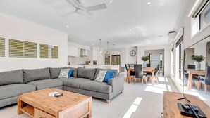A modern living room with a grey sectional sofa, a wooden coffee table, and a dining area with a wooden table and chairs.