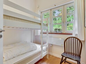 A bunk bed room with a window, a chair, and a radiator.