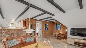 Un vaste espace de vie comprenant un canapé en cuir marron, une table basse en bois et un téléviseur.