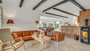 Un vaste espace de vie comprenant un grand canapé en cuir, une table basse en bois et une cheminée en briques.