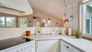 Cozinha moderna com painéis de madeira, fogão embutido, lava-louças e uma janela que permite entrada de luz natural.
