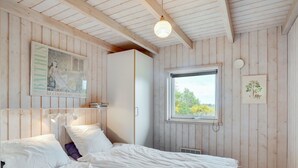 Quarto com cama, janela com vista e luminária fixada na parede.