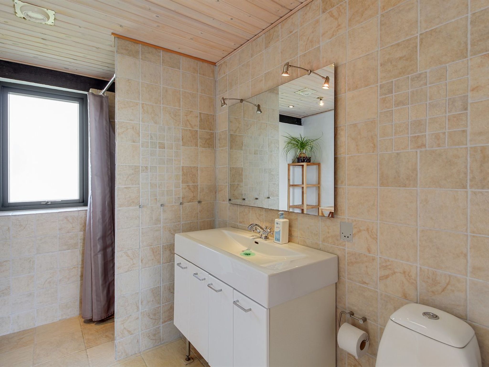A modern bathroom with a large mirror, a sink, and a toilet.