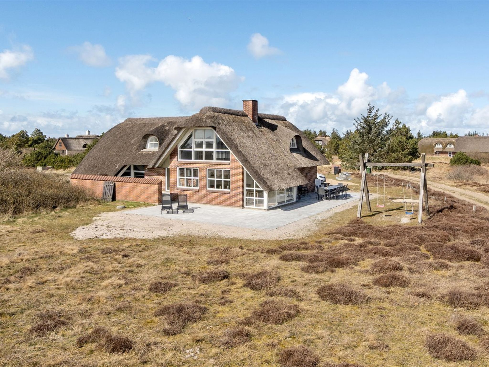 A house with a thatched roof, brick walls, and a patio area with outdoor furniture.