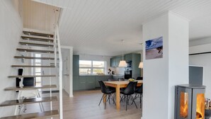 Een moderne keuken met een eethoek, een trap en een houtkachel.