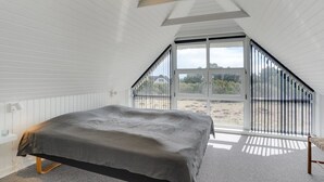 Een slaapkamer met een bed, een raam en een plafondlamp.