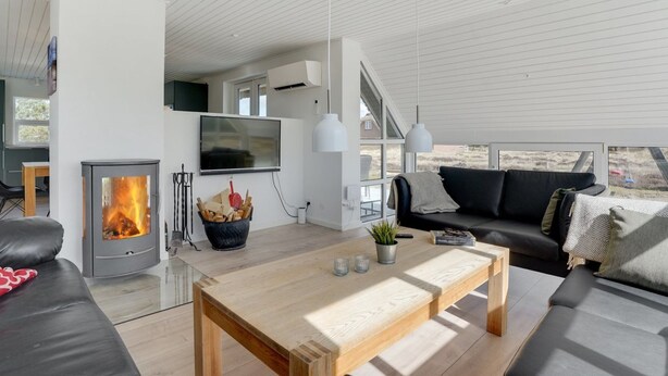 Een moderne woonkamer met een open haard, een grote televisie en een comfortabele zithoek.
