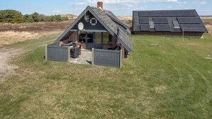 Ein kleines, gebäude mit einem Satteldach, einer Terrassenfläche und einem Solarpaneelhaus im Hintergrund.