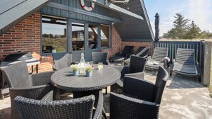 Ein überdachter Patio-Bereich mit Gartenmöbeln, einem Grill und einer Satellitenschüssel.