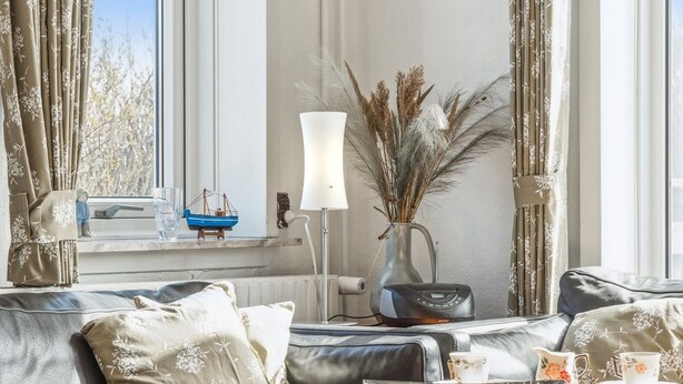 Ein gemütliches Wohnzimmer mit einer Couch, einem Couchtisch und einer Vase mit Trockenpflanzen.