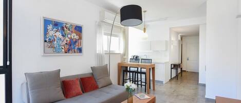 A modern living room with a sofa, a coffee table, and a dining area with a table and chairs.
