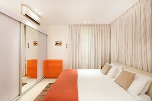 A hotel room with a bed, a wardrobe, a mirror, and a curtain.