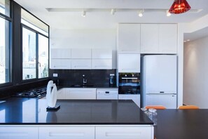 A modern kitchen with white cabinets, a black countertop, and a built-in stove.