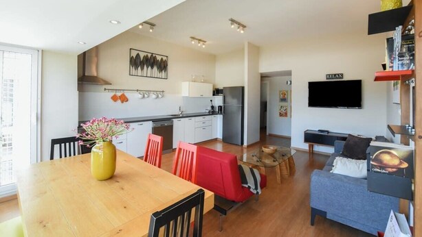 Un appartement moderne comprenant un coin repas, une cuisine, un salon et un téléviseur fixé au mur.
