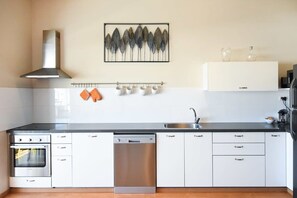 A modern kitchen with white cabinets, a stainless steel dishwasher, and a built-in oven. - Red by HolyGuest (Tel Aviv)