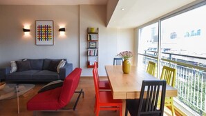 Un espace de vie moderne comprenant un canapé, des fauteuils rouges, une table à manger en bois et une bibliothèque.