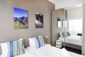 Een hotelkamer met een bed, een nachtkastje, een spiegel en twee ingelijste foto’s aan de muur.
