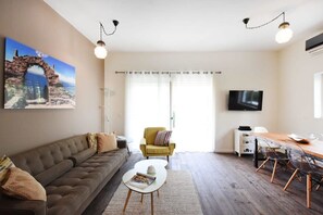 Un salon comprenant un canapé, un fauteuil, une table basse et une table à manger.