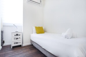 A bedroom with a bed, a nightstand, and a window.