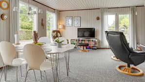 Un salon moderne comprenant un coin repas, un téléviseur, des étagères et une grande fenêtre.