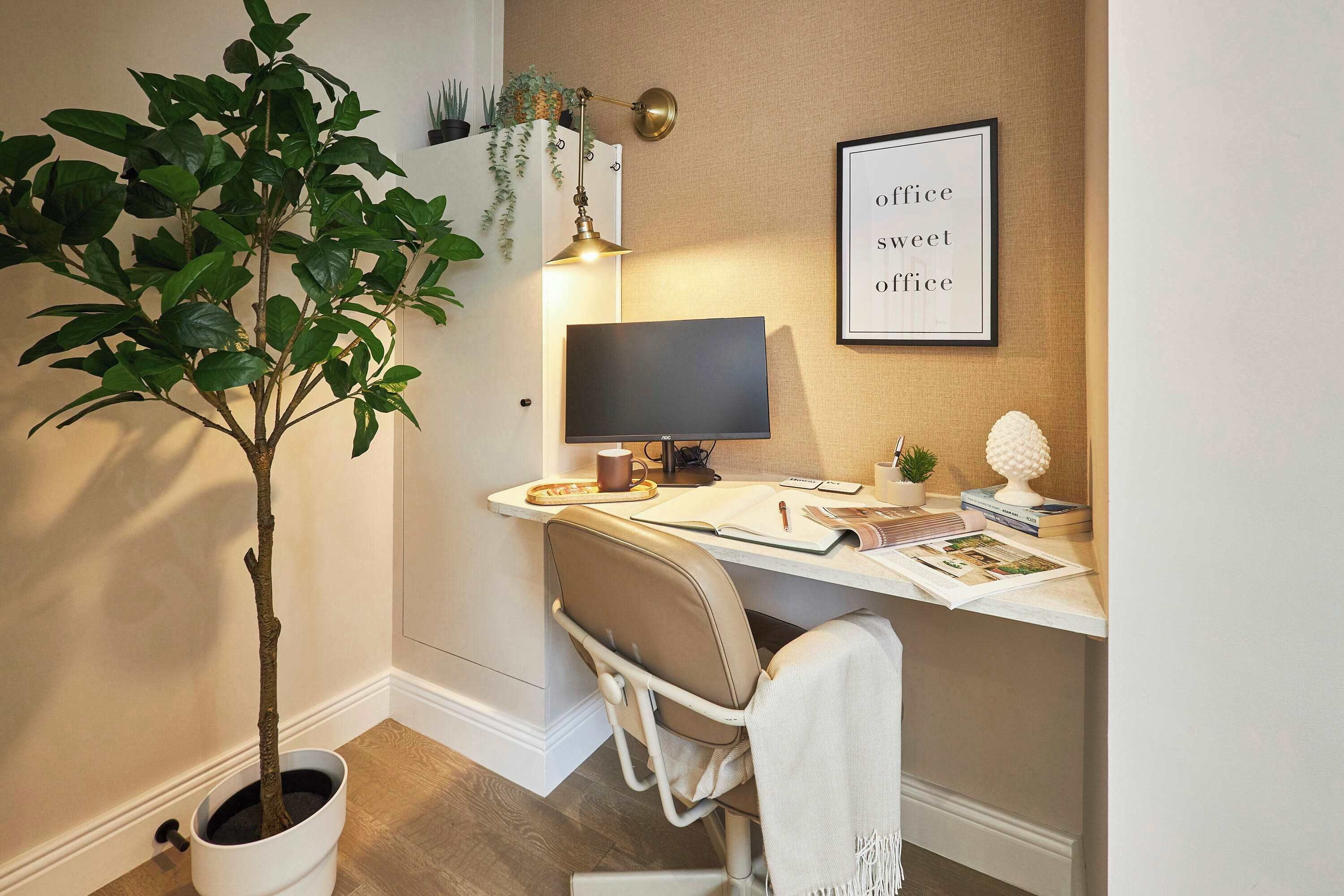Una oficina en casa con escritorio, silla, computadora y planta en maceta.