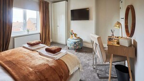 Une chambre d’hôtel avec un lit, un bureau, une télévision et une fenêtre avec des rideaux.