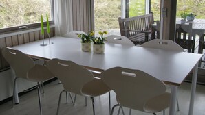 A dining area with a long table, white chairs, and potted plants. - "Elsa" - 700m from the sea by Interhome (Oksbøl)