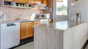 A modern kitchen with wooden cabinets, a built-in dishwasher, a microwave, and a large island. - "Elsa" - 700m from the sea by Interhome (Oksbøl)